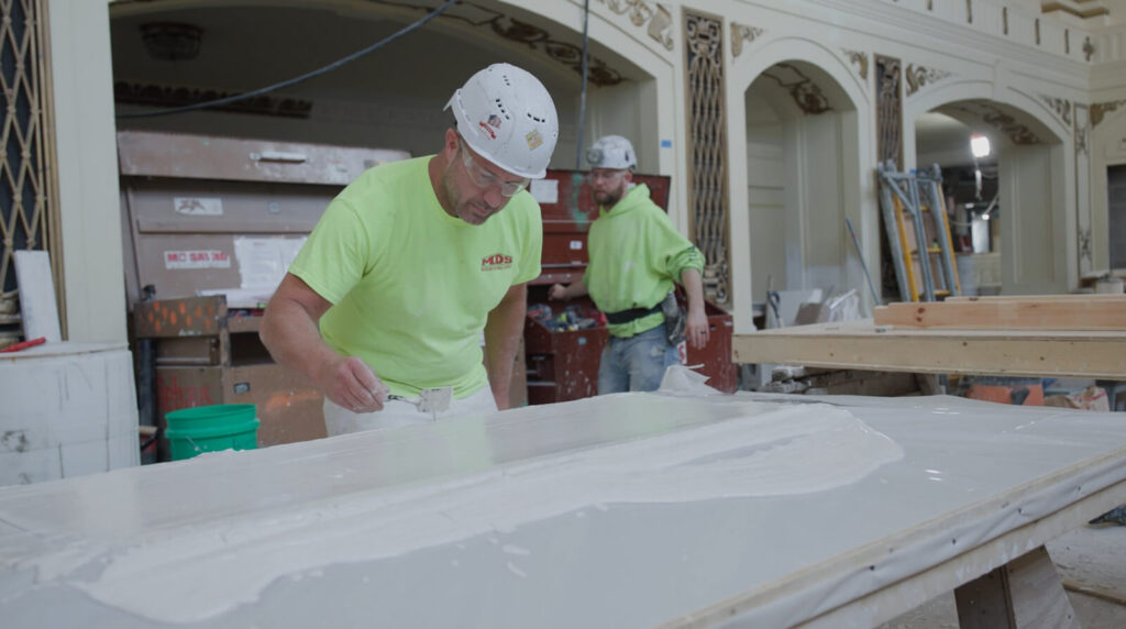 At Powell Hall, Ornamental Details Are Carefully Recreated 1 Craftsman applying wet plaster with precision tools to fabricate custom ornamental molding for commercial historic preservation.