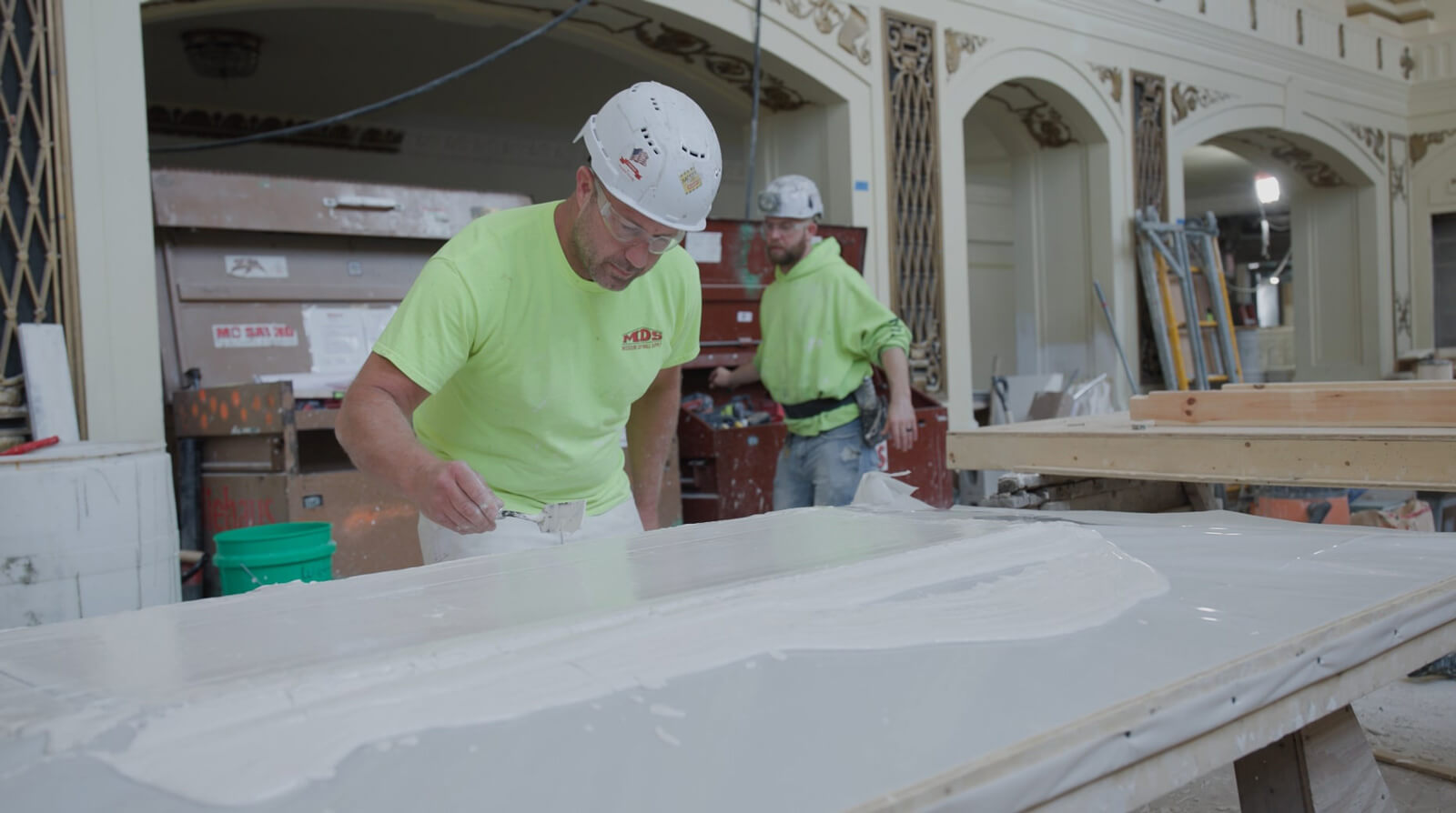 Craftsman applying wet plaster with precision tools to fabricate custom ornamental molding for commercial historic preservation.
