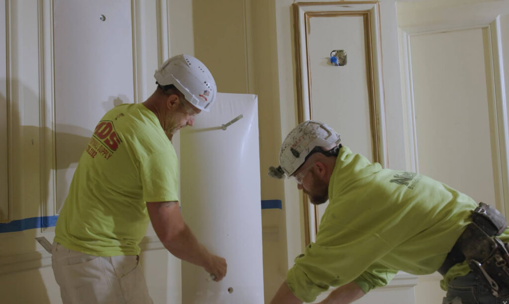 At Powell Hall, Ornamental Details Are Carefully Recreated 2 Two Niehaus Building Services craftsmen in safety helmets carefully repairing plaster trim and historic wall moldings.